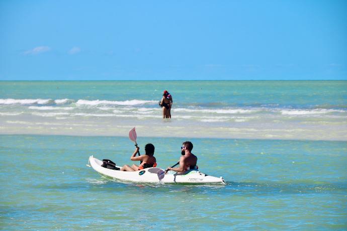 2 women sitting on white surfboard on beach during daytime